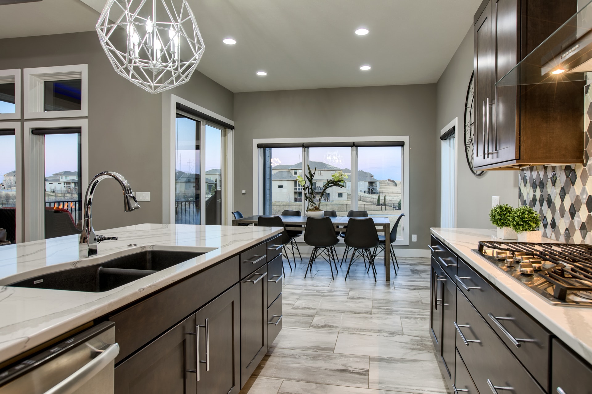 Kitchen and dining area with marble island, geometric chandelier and sliding glass doors to backyard